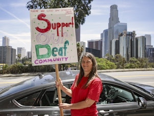 caption: A deaf mother of a hearing daughter supports a proposal to overhaul education for deaf and hard of hearing students in the Los Angeles Unified School District. Supporters of the proposal rally outside Los Angeles Unified School District Headquarters earlier this year in Los Angeles.