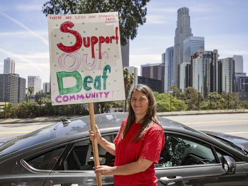 caption: A deaf mother of a hearing daughter supports a proposal to overhaul education for deaf and hard of hearing students in the Los Angeles Unified School District. Supporters of the proposal rally outside Los Angeles Unified School District Headquarters earlier this year in Los Angeles.