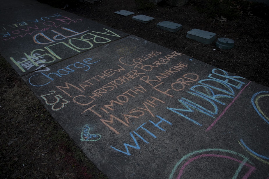 caption: Chalk writing urging that the officers involved in the death of Manuel Ellis be charged with murder was left outside of the Tacoma Police Department on Sunday, February 28, 2021, following a silent march honoring the 33-year-old musician and father of two who was killed by Tacoma police one year ago. 'You murdered Manuel Ellis' was also written along the sidewalk along Martin Luther King Jr. Way.