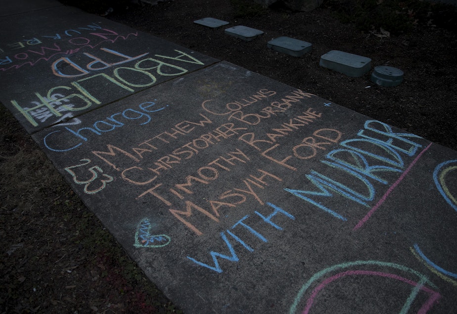 caption: Chalk writing urging that the officers involved in the death of Manuel Ellis be charged with murder was left outside of the Tacoma Police Department on Sunday, February 28, 2021, following a silent march honoring the 33-year-old musician and father of two who was killed by Tacoma police one year ago. 'You murdered Manuel Ellis' was also written along the sidewalk along Martin Luther King Jr. Way.