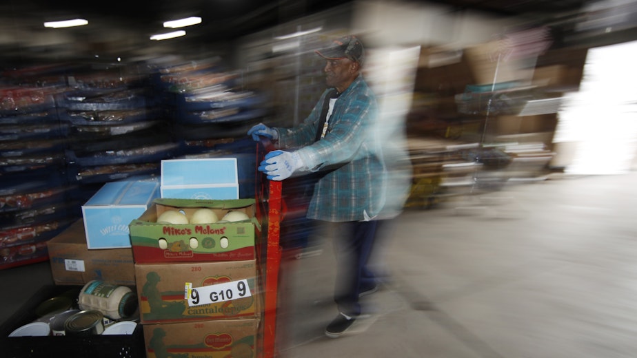 caption: Volunteer Earl Banks guides a load of food to a waiting van at a Denver branch of the Volunteers of America.