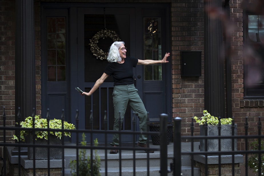caption: A Wallingford resident dances along to the music as the Seattle Quarantine Parade drives by on Friday, May 8, 2020, in Seattle.