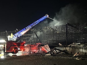 caption: Fire crews spray water on rubble at the Lineage Logistics fire in Finley, Washington. The fire started April 21.