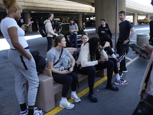 caption: Players and staff of the New York Liberty WNBA basketball team wait to board buses at Harry Reid International Airport, Wednesday, June 28, 2023, in Las Vegas.