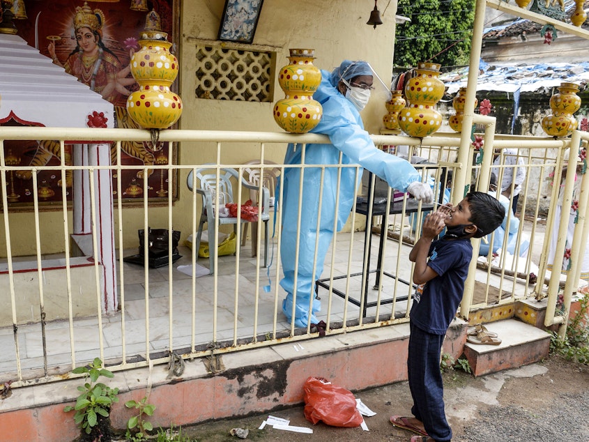 caption: A health worker collects a swab sample from a boy for a coronavirus test at a temporary collection center at a Hindu temple in Hyderabad, the capital of the Indian state of Telangana, on Sept. 30, 2020.