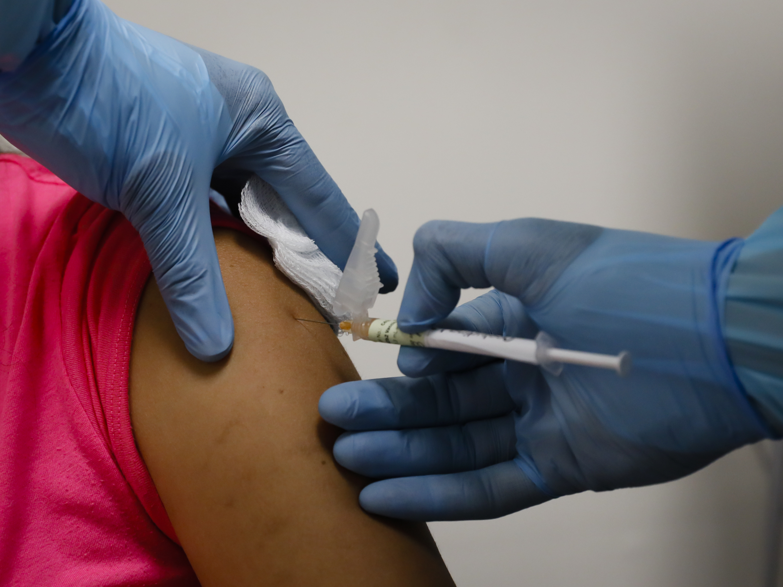 caption: A health worker injects a woman during clinical trials for a COVID-19 vaccine in Hollywood, Fla., last month.