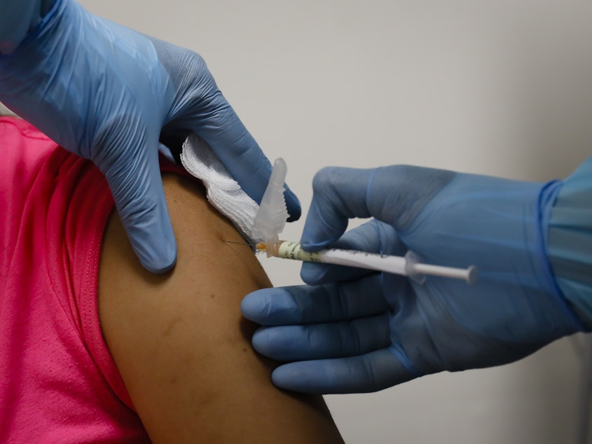 caption: A health worker injects a woman during clinical trials for a COVID-19 vaccine in Hollywood, Fla., last month.