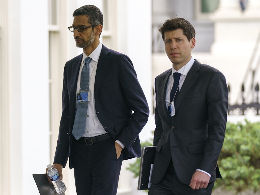 caption: Alphabet CEO Sundar Pichai, left, and OpenAI CEO Sam Altman arrive to the White House for a meeting in May.