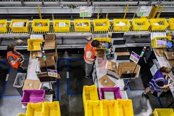 caption: Amazon employees sort packages at a new warehouse in Arlington, Washington.