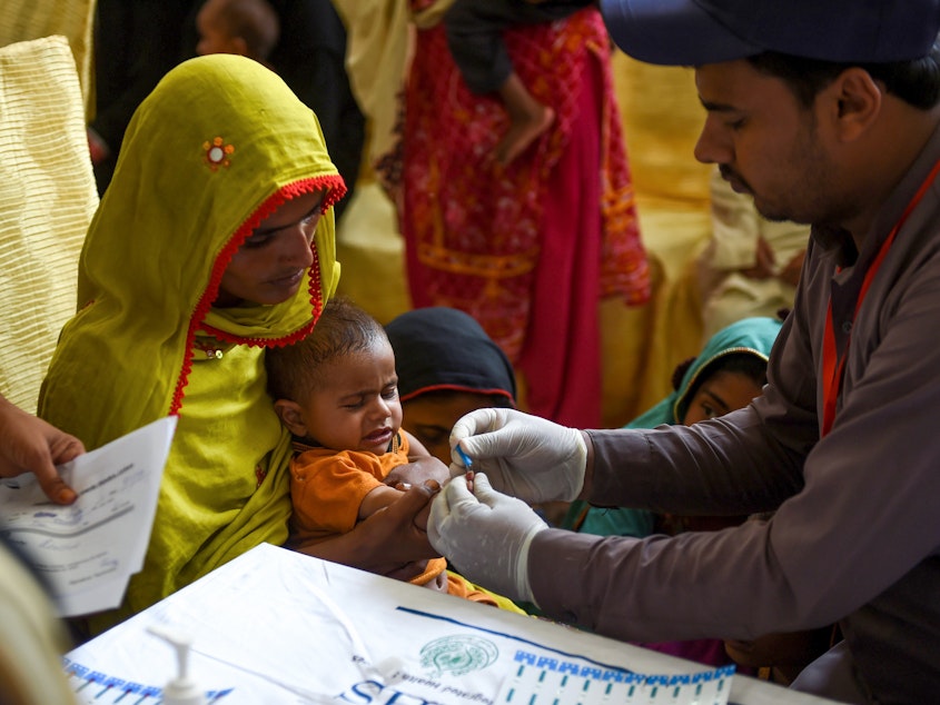 caption: A paramedic takes a blood sample from a baby for an HIV test in Larkana, Pakistan, on May 9. The government has been offering screenings in response to an HIV outbreak.