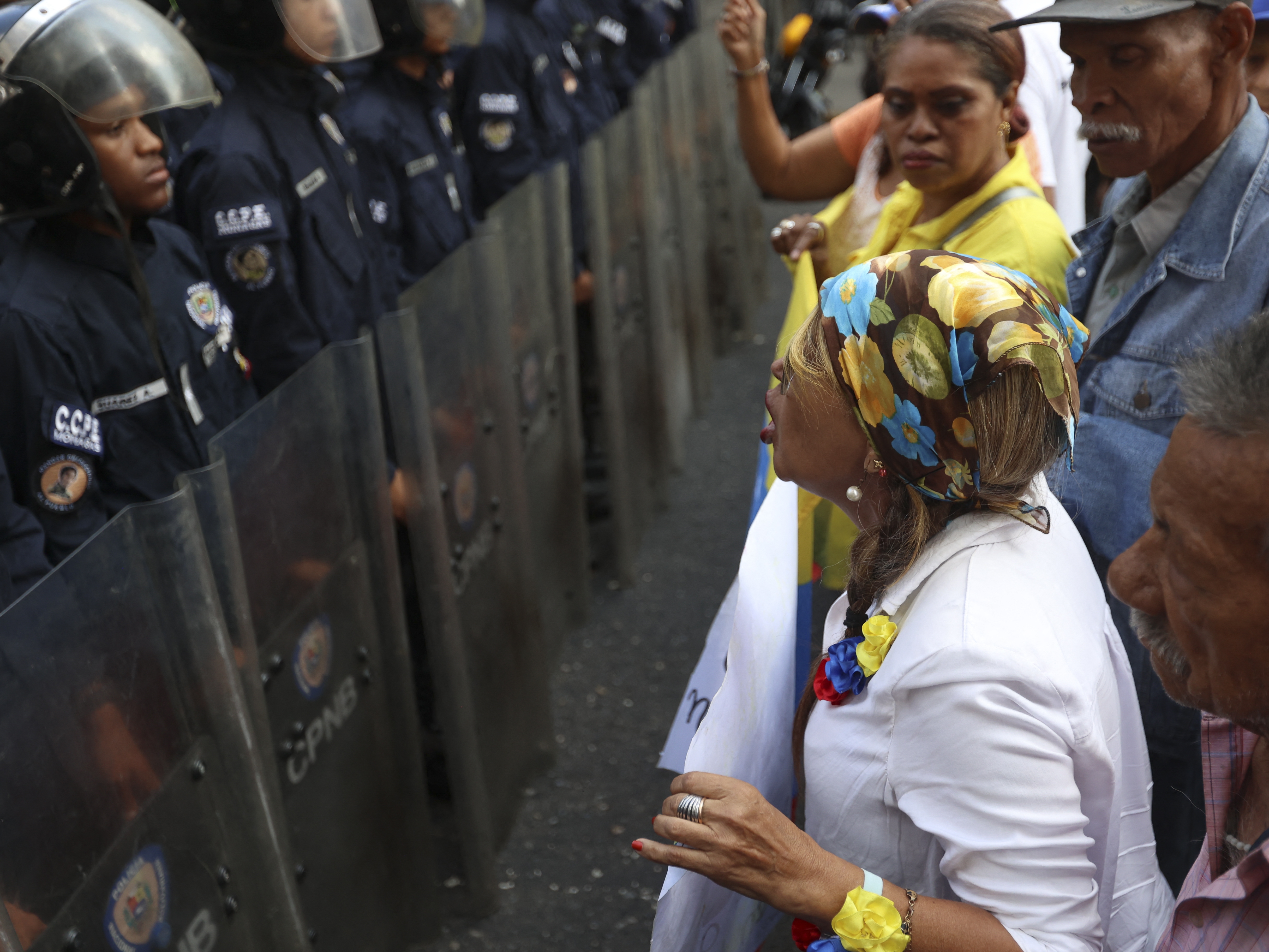 caption: Retired education workers shout slogans in front of a line of riot police during a protest to demand the immediate approval of the Civil and Labor Amnesty Law in Caracas on Feb.10, 2026.