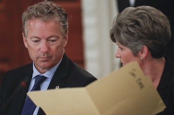 caption: Sen. Rand Paul, R-Ky., performed the Heimlich maneuver on Sen. Joni Ernst, R-Iowa as she was choking Thursday during a closed-door GOP lunch. Here, Paul and Ernst look over a folder provided to them by the White House, during a luncheon in 2017 in the State Dinning Room of the White House.