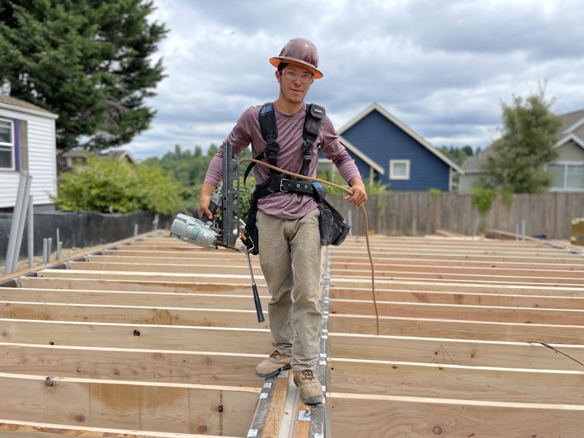caption: Elio Gonzalez finishes off the first floor at a Madison Valley building site in Seattle. 