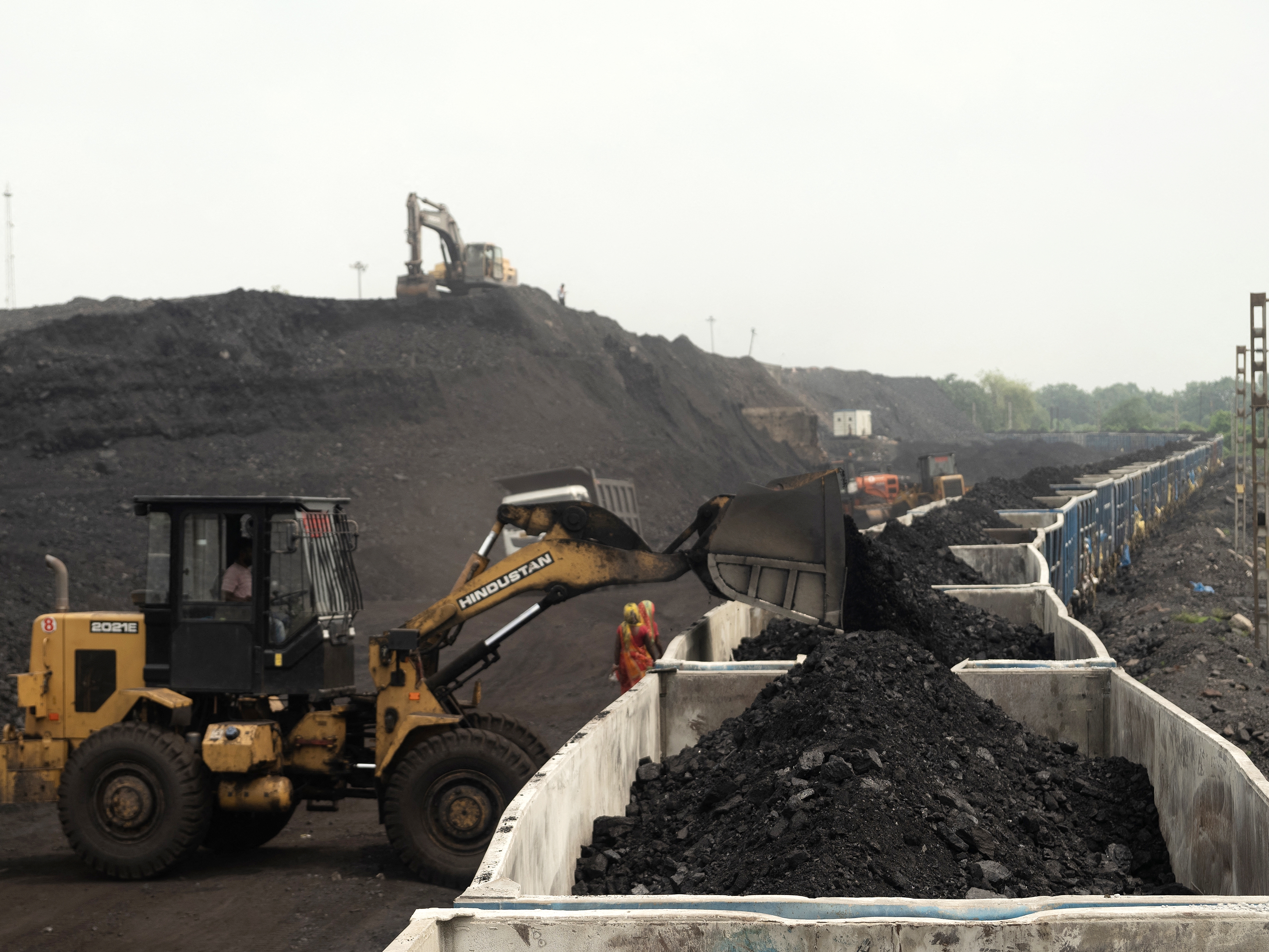 caption: On the outskirts of Dhanbad, in India's Jharkhand state, heaps of coal are loaded onto a train car in August. India is the world's third-largest greenhouse gas polluter and relies heavily on coal for electricity generation.