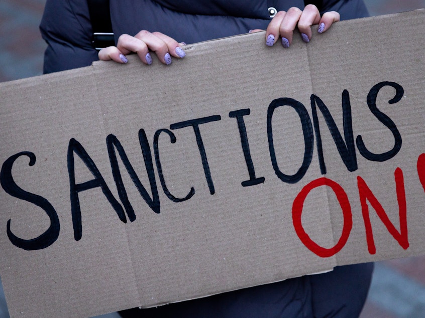 caption: KYIV, UKRAINE - FEBRUARY 21: A group of people hold signs at the front of the Ukrainian Foreign Ministry during a protest calling for the European Union to impose additional sanctions against Russia on February 21, 2022 in Kyiv, Ukraine.