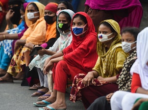 caption: Workers from the garment sector block a road during a protest to demand payment of due wages, in Dhaka, Bangladesh, in April 2020. They claimed that factories had not paid them after retailers and brands cancelled orders due to worldwide lockdown measures.