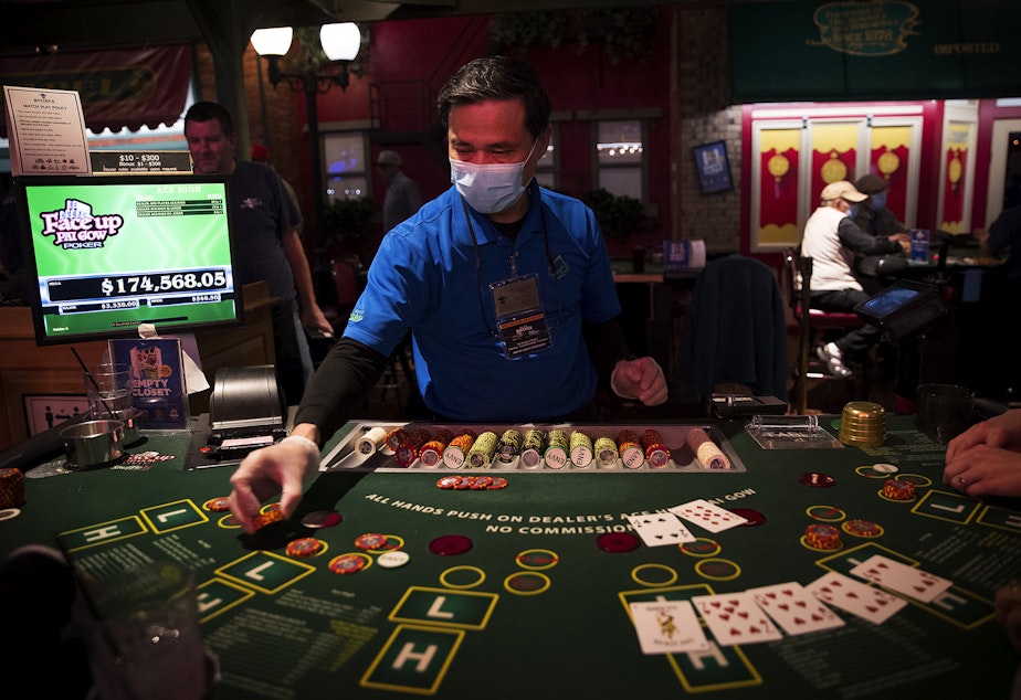 caption: Phuoc N. deals pai gow poker on Tuesday, May 17, 2022, at the Great American Casino in Tukwila. 
