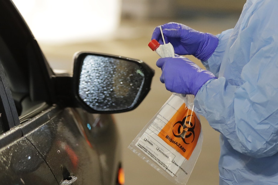 caption: A nurse at a drive up COVID-19 coronavirus testing station, set up by the University of Washington Medical Center, on Friday, March 13, in Seattle. (Ted S. Warren/AP)