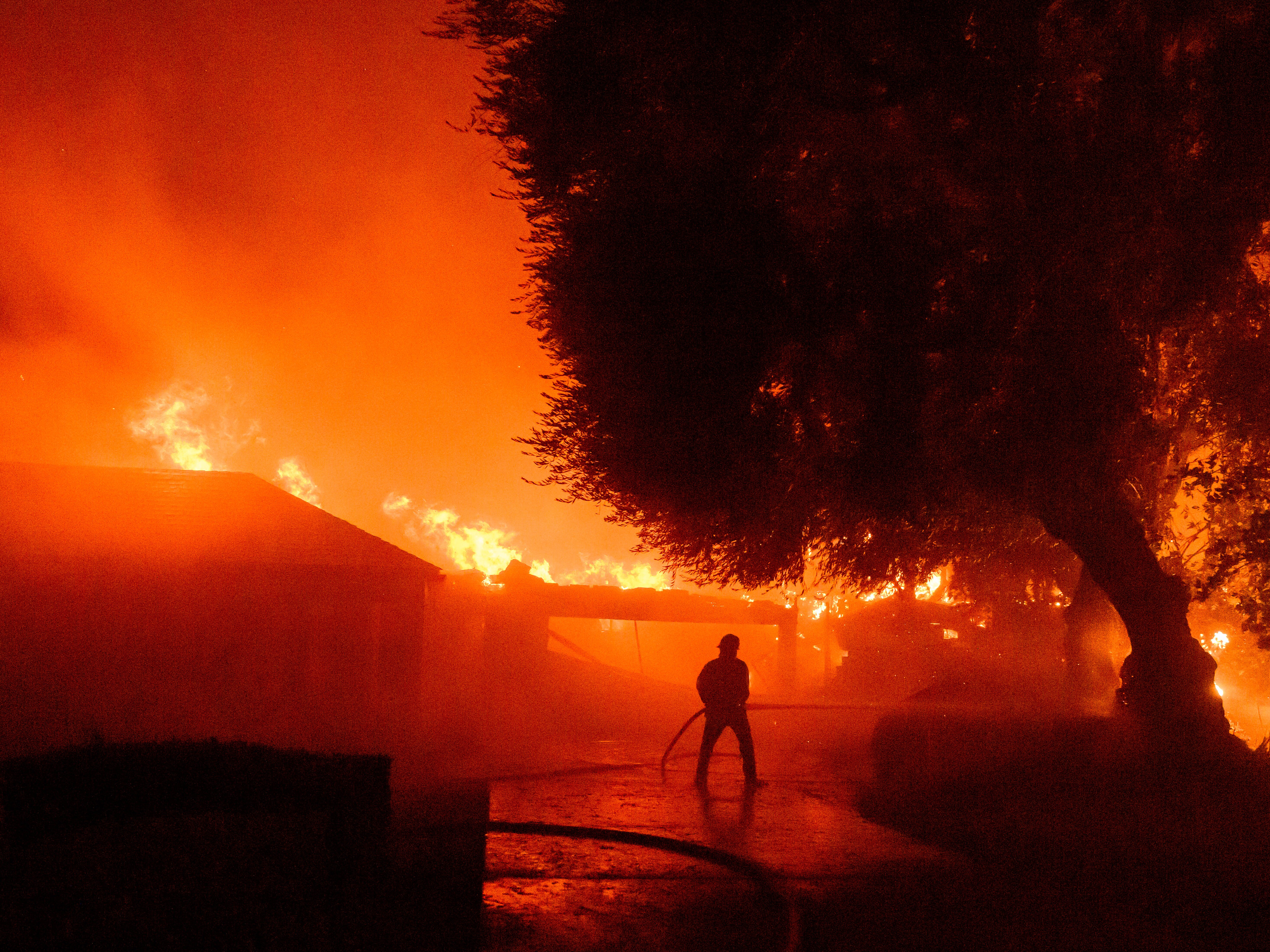 caption: A firefighter works at the scene as dozens of homes burn during the Eaton fire in the Altadena area of Los Angeles County, California on Jan. 7, 2025.