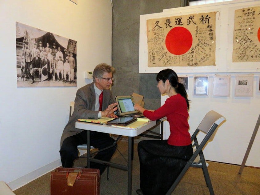 caption: Obon Society co-founders Rex and Keiko Ziak working remotely during a temporary exhibit of yosegaki hinomaru flags in Portland in 2015.