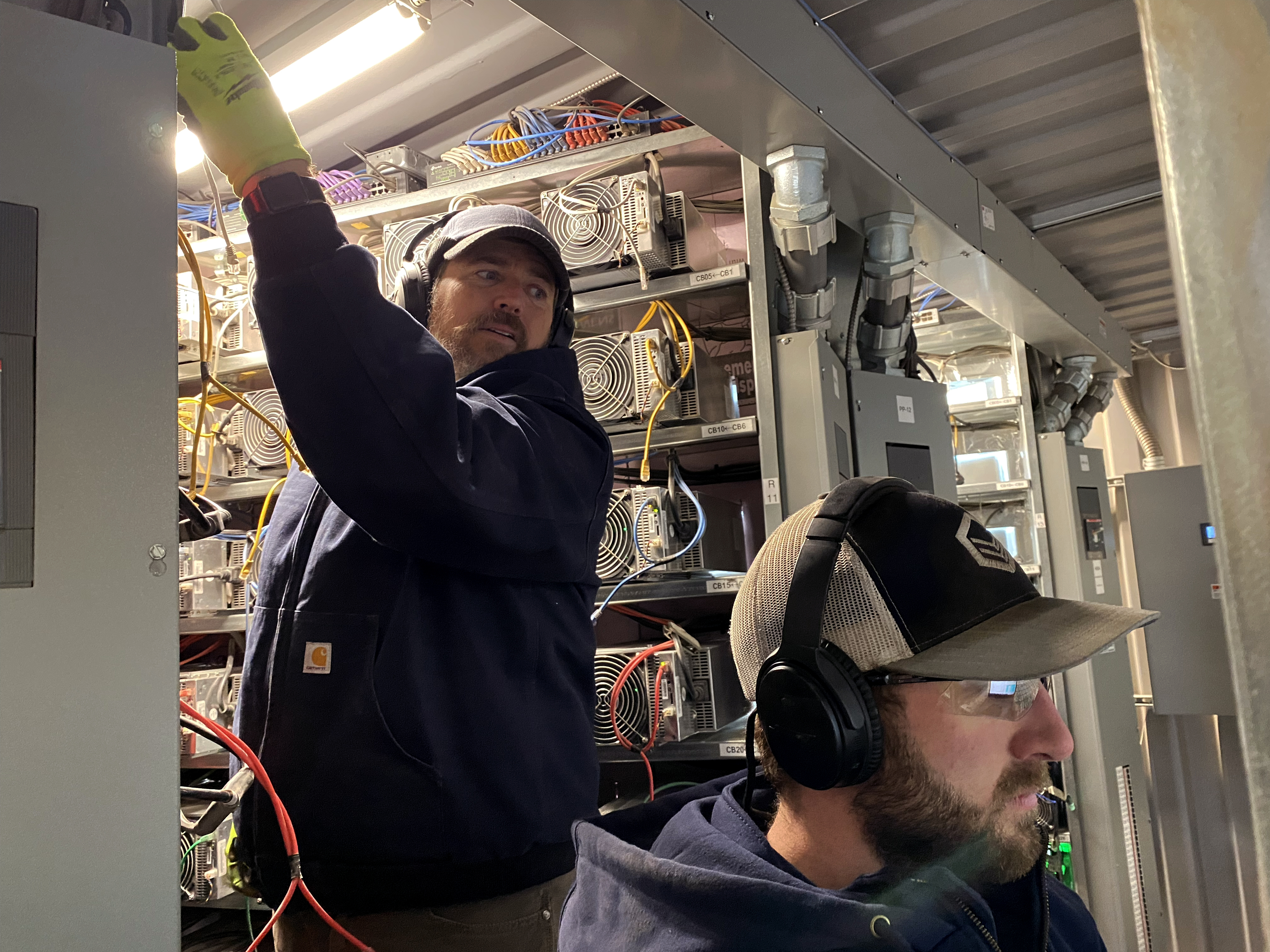 caption: Workers install cryptocurrency mining computers inside a converted shipping container at the Compute North facility in Nebraska.