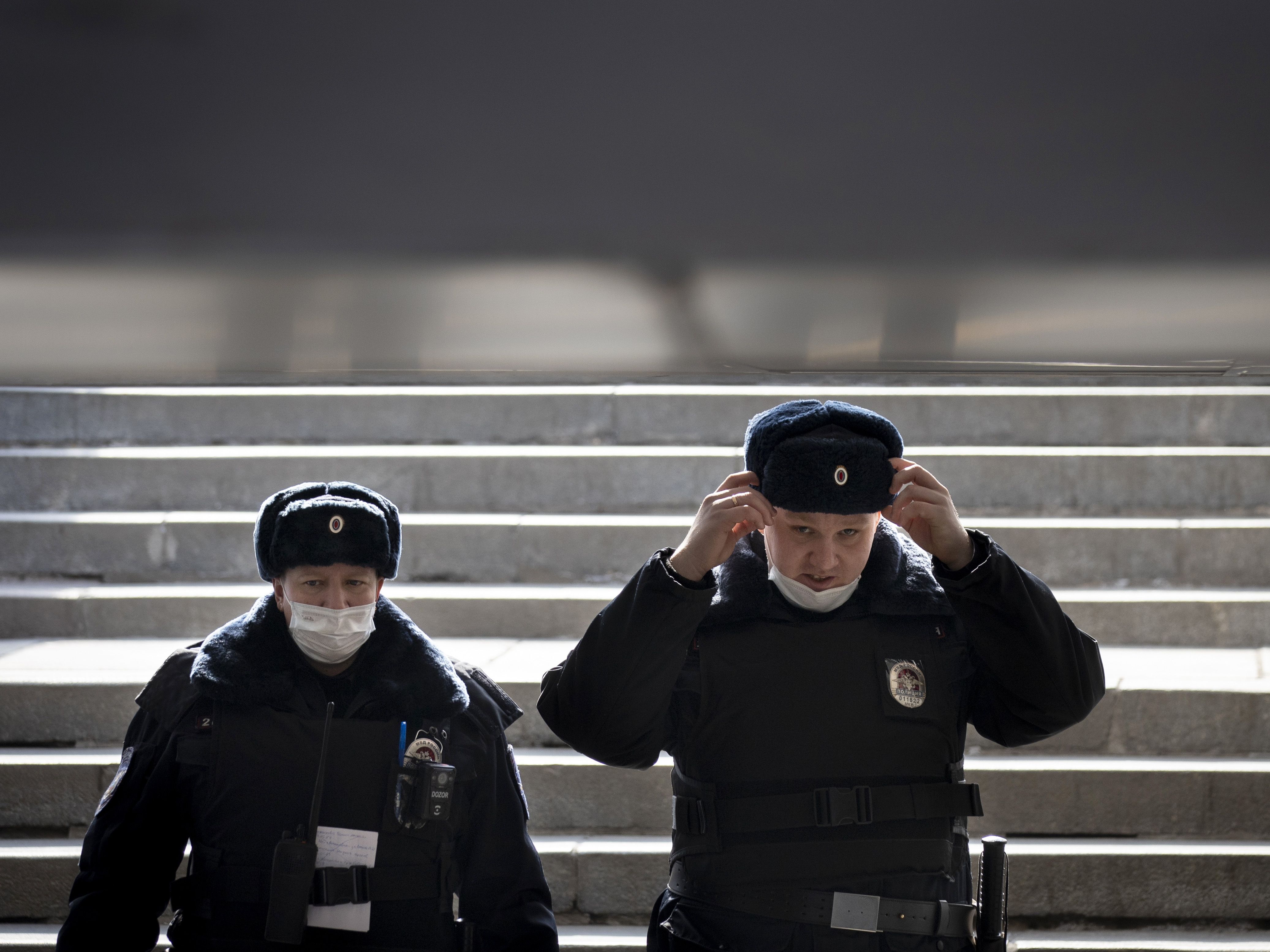 caption: Russian police officers, wearing face masks to guard against the coronavirus, descend into a pedestrian underpass as they patrol to enforce a self-isolation regime in Moscow.