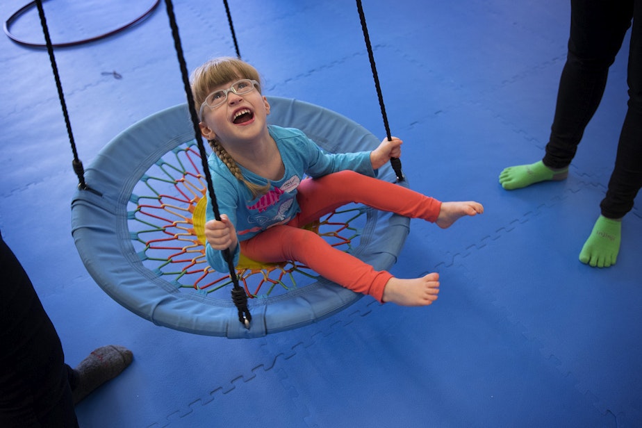 caption: Lillian Rockett, 4, laughs as she is pushed on a circular swing on Sunday, October 1, 2017, at We Rock the Spectrum Kid's Gym in Bellevue. 