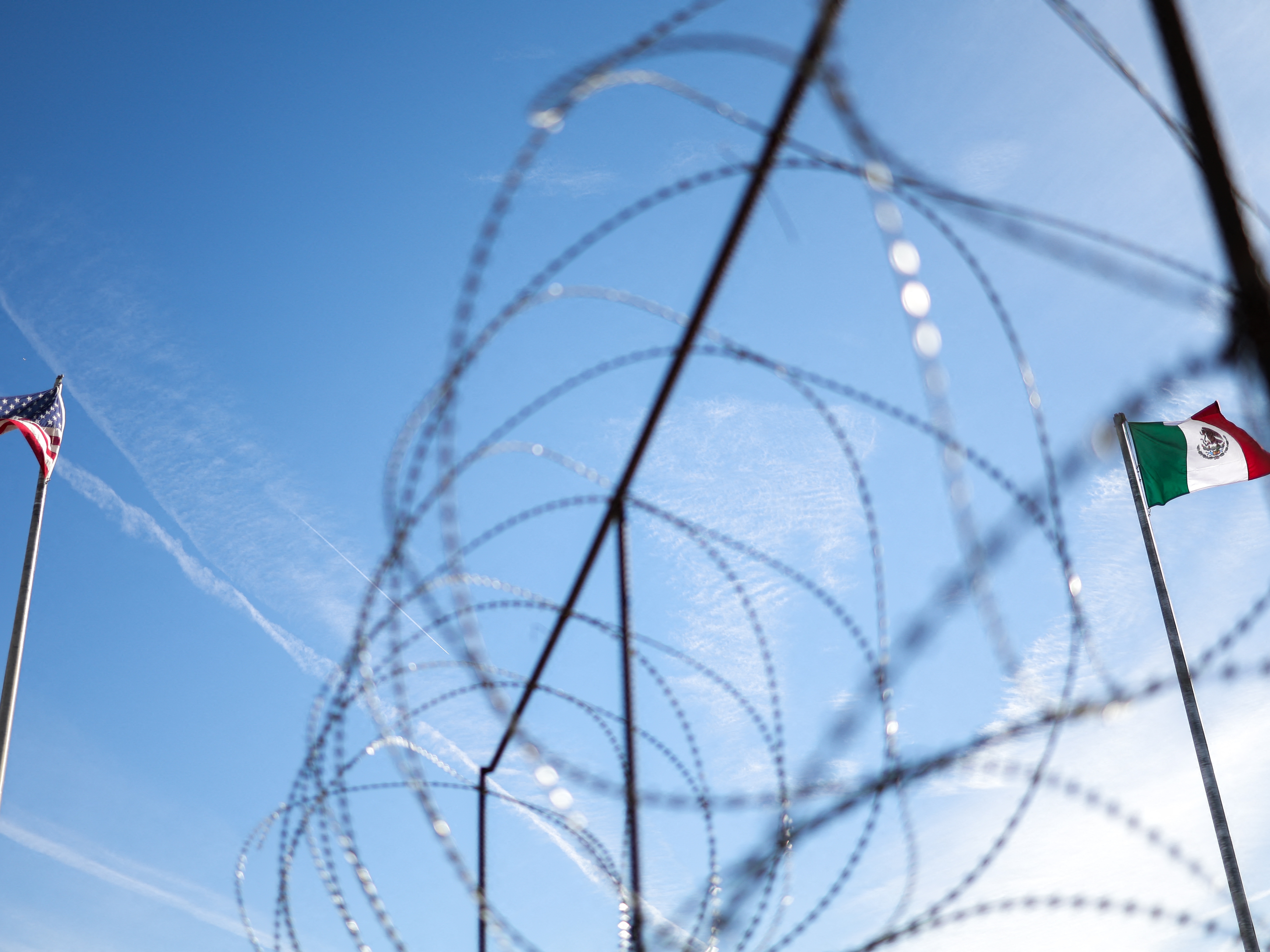 caption: An American flag (L) and Mexican flag (R) fly along the US-Mexico border in El Paso, Texas in January 2025.