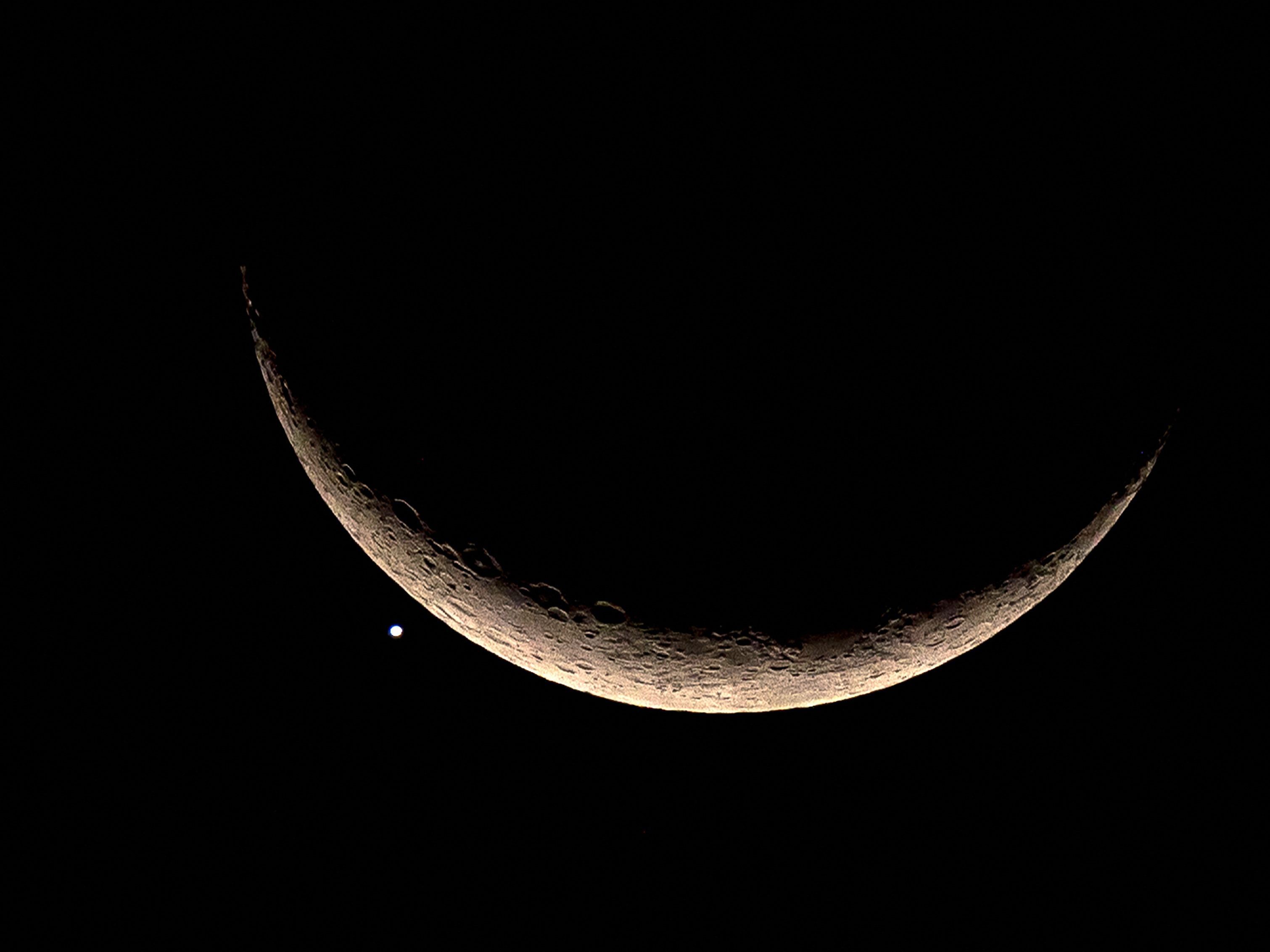 caption: The crescent moon and Venus are pictured in Bangkok in 2023. A failed Soviet lander bound for Venus in 1972 and stranded in orbit is finally set to return to Earth.