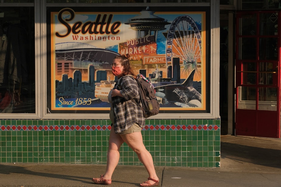 caption: A woman wears a mask as she walks down Pike Street in downtown, August 3, 2021. Although there is no longer a mask mandate, many are still choosing to mask up both inside and out as Washington sees further spread of the delta variant.