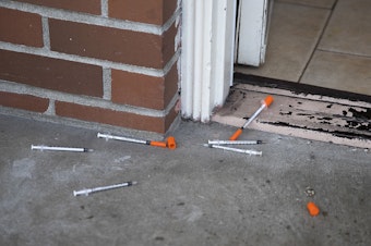 caption: Needles are shown in the doorway of a room at Sun Hill Motel on Wednesday, March 21, 2018, on Aurora Avenue North in Seattle. 