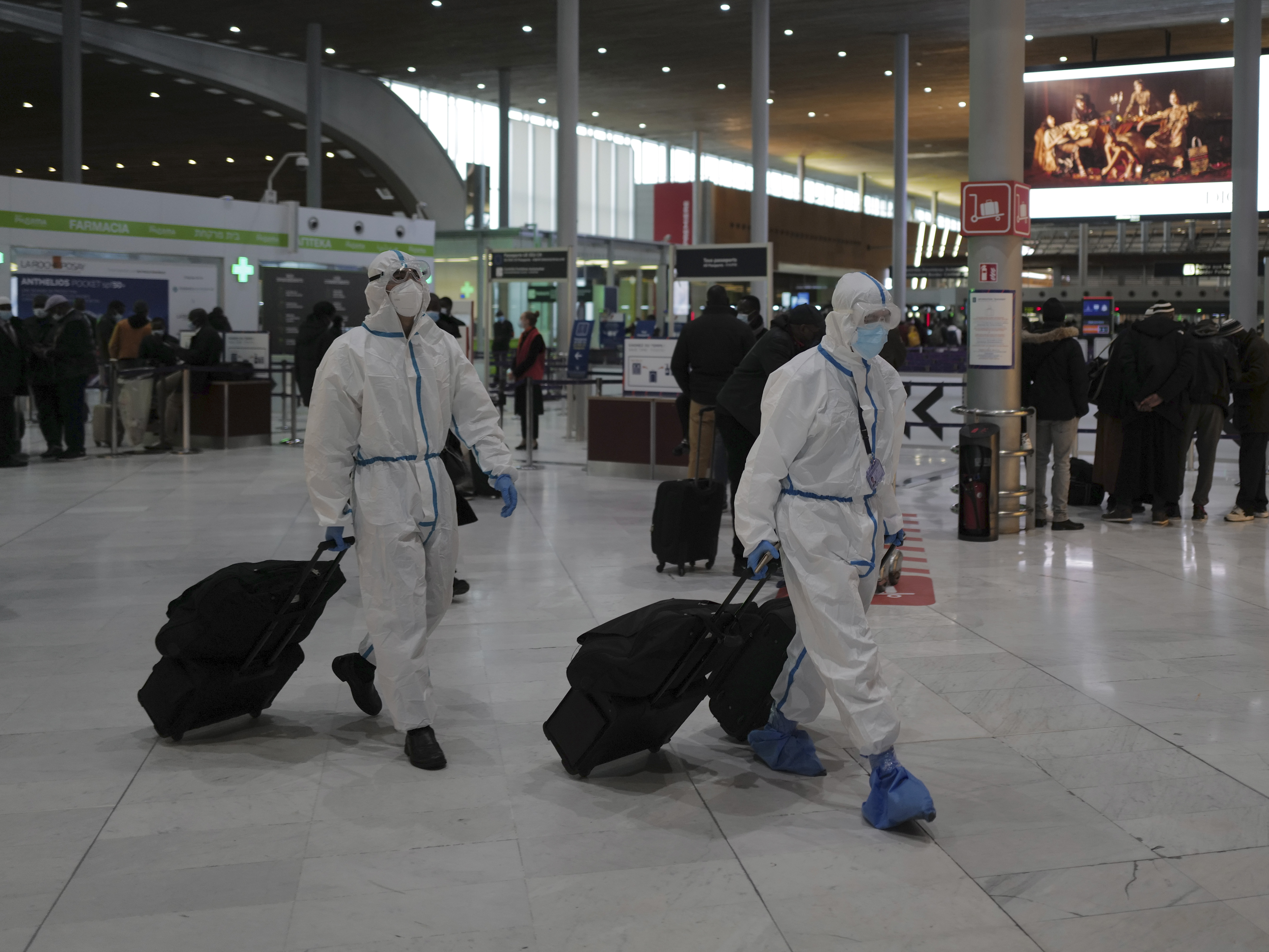 caption: Global travel continues to be risky because of the coronavirus. Earlier this year, passengers from Taiwan wear protective gear as they arrive at France's Charles de Gaulle Airport, and just this week, the U.S. issued over 100 new travel advisories.