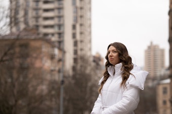 caption: Lytvynova stands near an apartment building in her Kyiv neighborhood that was damaged by multiple Russian strikes over the course of the war.
