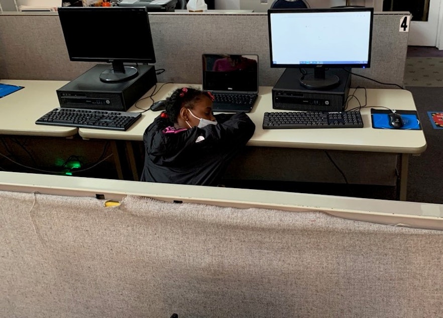 caption: A fifth grader naps before it's time to login for her remote classes, at the Central Area Youth Association.