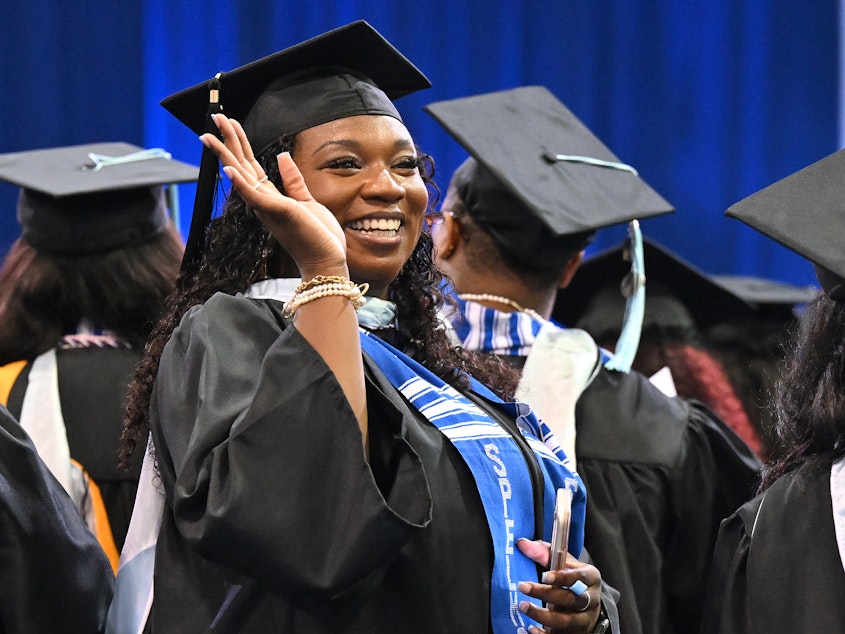 caption: A Spelman College graduate waves during the school's 2023 commencement ceremony on May 21. Recent college graduates are due to make their first student loan payments in the coming weeks.