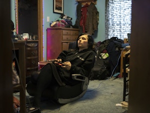 caption: Robinson plays Red Dead Redemption 2 in her bedroom.