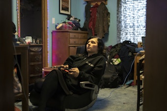 caption: Robinson plays Red Dead Redemption 2 in her bedroom.