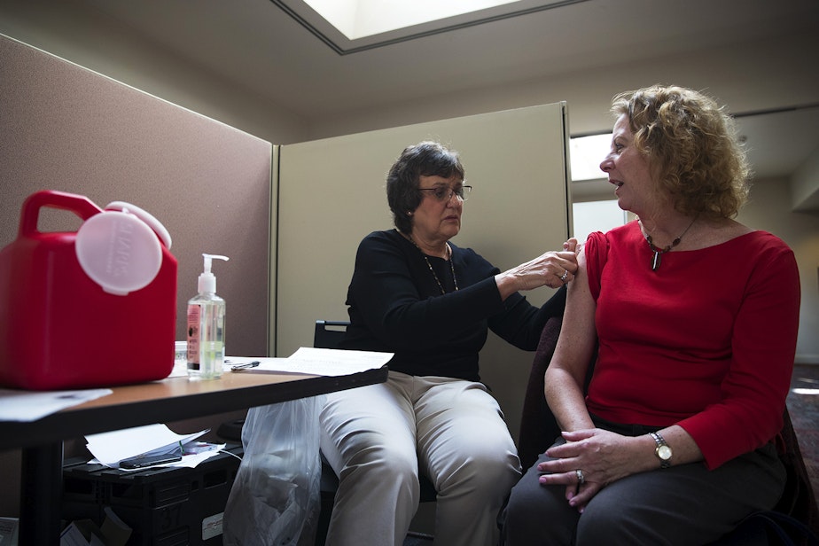 caption: Registered nurse Jeanice Smith, left, administers a flu shot for Cynthia Caci on Tuesday, October 1, 2019, at UW Tower in Seattle.