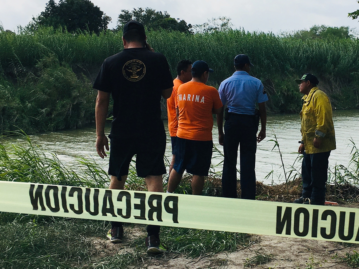 caption: Authorities stand behind yellow warning tape along the Rio Grande bank where the bodies of Salvadoran migrant Óscar Alberto Martínez Ramírez and his 23-month-old daughter, Valeria, were found, in Matamoros, Mexico on Monday, after they drowned trying to cross the river to Brownsville, Texas.