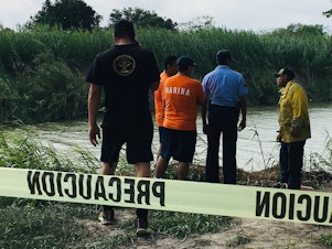 caption: Authorities stand behind yellow warning tape along the Rio Grande bank where the bodies of Salvadoran migrant Óscar Alberto Martínez Ramírez and his 23-month-old daughter, Valeria, were found, in Matamoros, Mexico on Monday, after they drowned trying to cross the river to Brownsville, Texas.