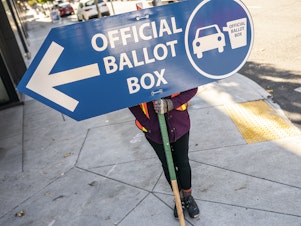 caption: An election worker directs voters to a ballot drop-off location in 2020 in Portland, Ore. Oregon is among the states waiting for the Biden administration to greenlight plans to automatically register eligible voters when they apply to enroll in Medicaid.