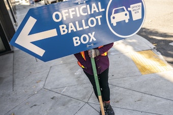 caption: An election worker directs voters to a ballot drop-off location in 2020 in Portland, Ore. Oregon is among the states waiting for the Biden administration to greenlight plans to automatically register eligible voters when they apply to enroll in Medicaid.