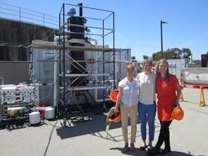 caption: Anne Schauer-Gimenez (left) Allison Pieja (center) and Molly Morse of Mango Materials stand next to the biopolymer fermenter at a sewage treatment plant by the San Francisco Bay. The fermenter feeds bacteria the methane they need to produce a biological form of plastic.