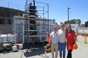 caption: Anne Schauer-Gimenez (left) Allison Pieja (center) and Molly Morse of Mango Materials stand next to the biopolymer fermenter at a sewage treatment plant by the San Francisco Bay. The fermenter feeds bacteria the methane they need to produce a biological form of plastic.