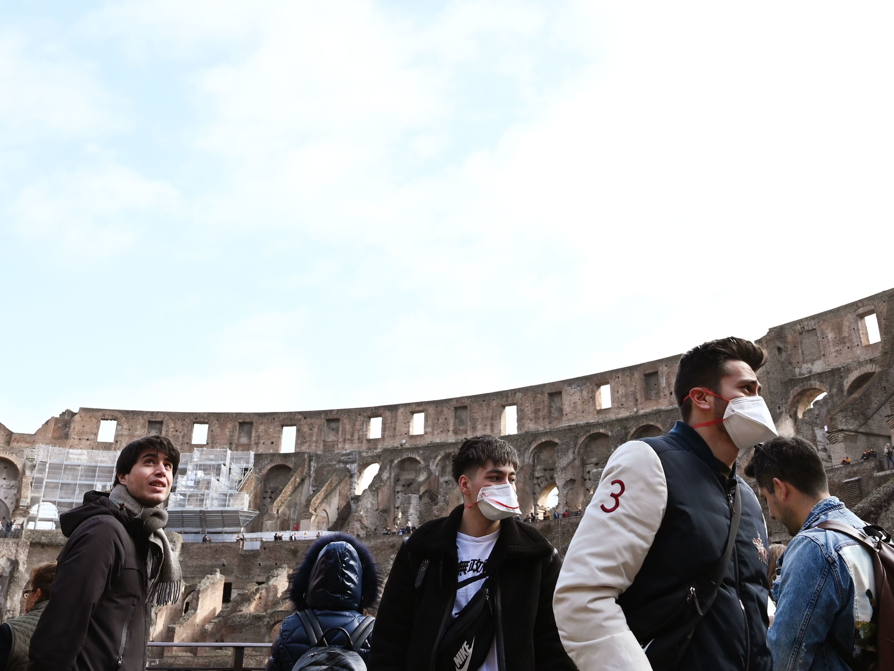 caption: Tourists wearing respiratory masks visit the Coliseum in Rome on Friday. Italy's coronavirus cases have continued to rise, making it one of the hardest-hit countries.