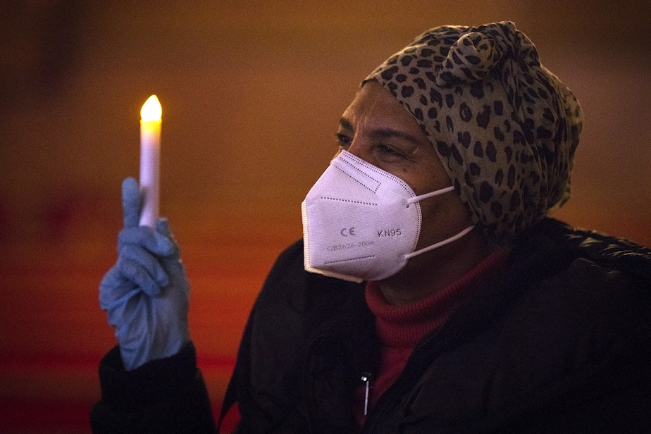 caption: Frehiwot Bruce holds a candle in the air while attending the 'Mourning into Unity' prayer vigil led by Reverend Carey Anderson in response to the coronavirus pandemic on Monday, October 19, 2020, at Seattle's First A-M-E Church on Capitol Hill. 