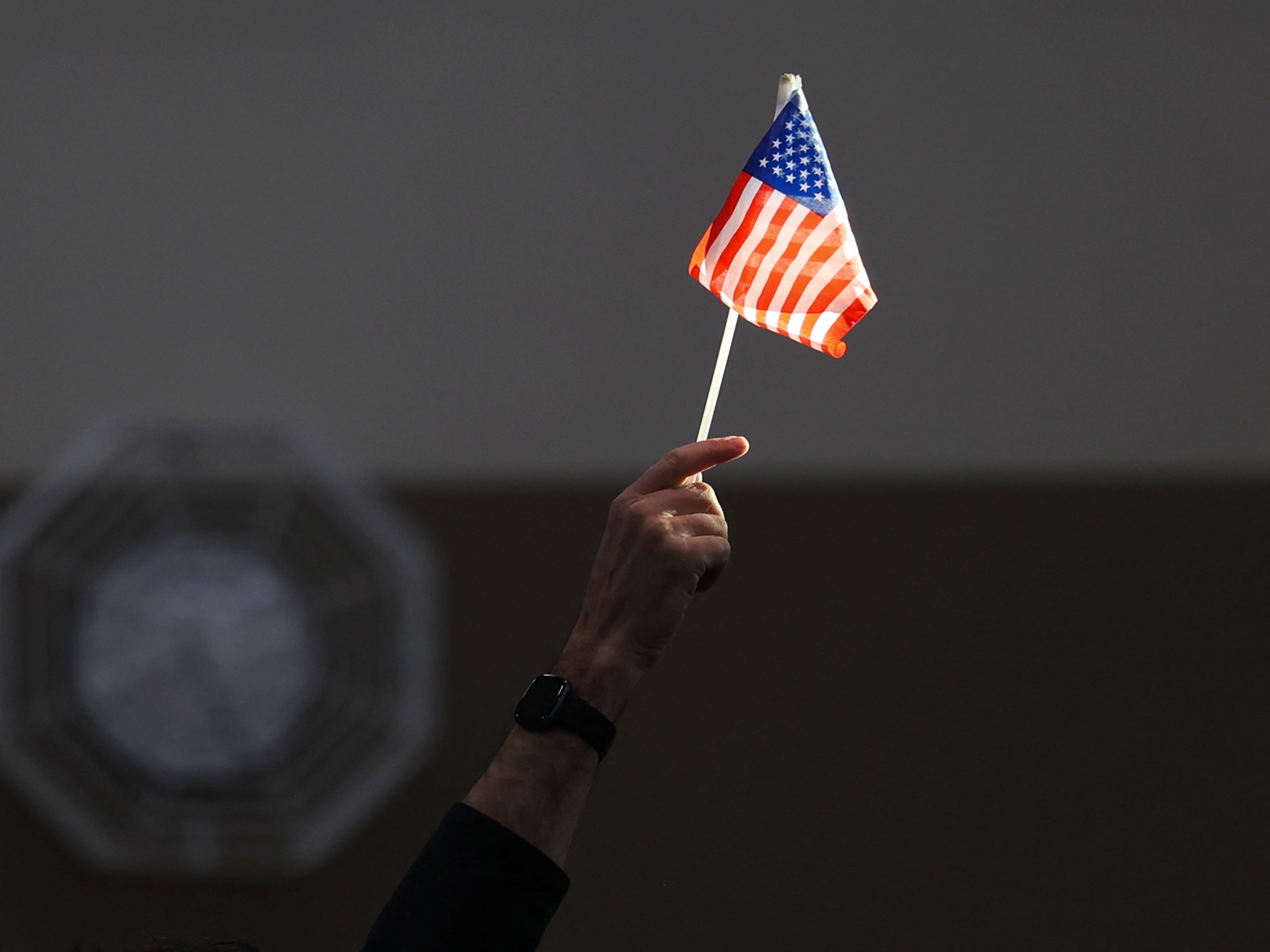 caption: An election worker raises a U.S. flag while assisting voters at a polling station in Las Vegas on Election Day, Nov. 5, 2024.