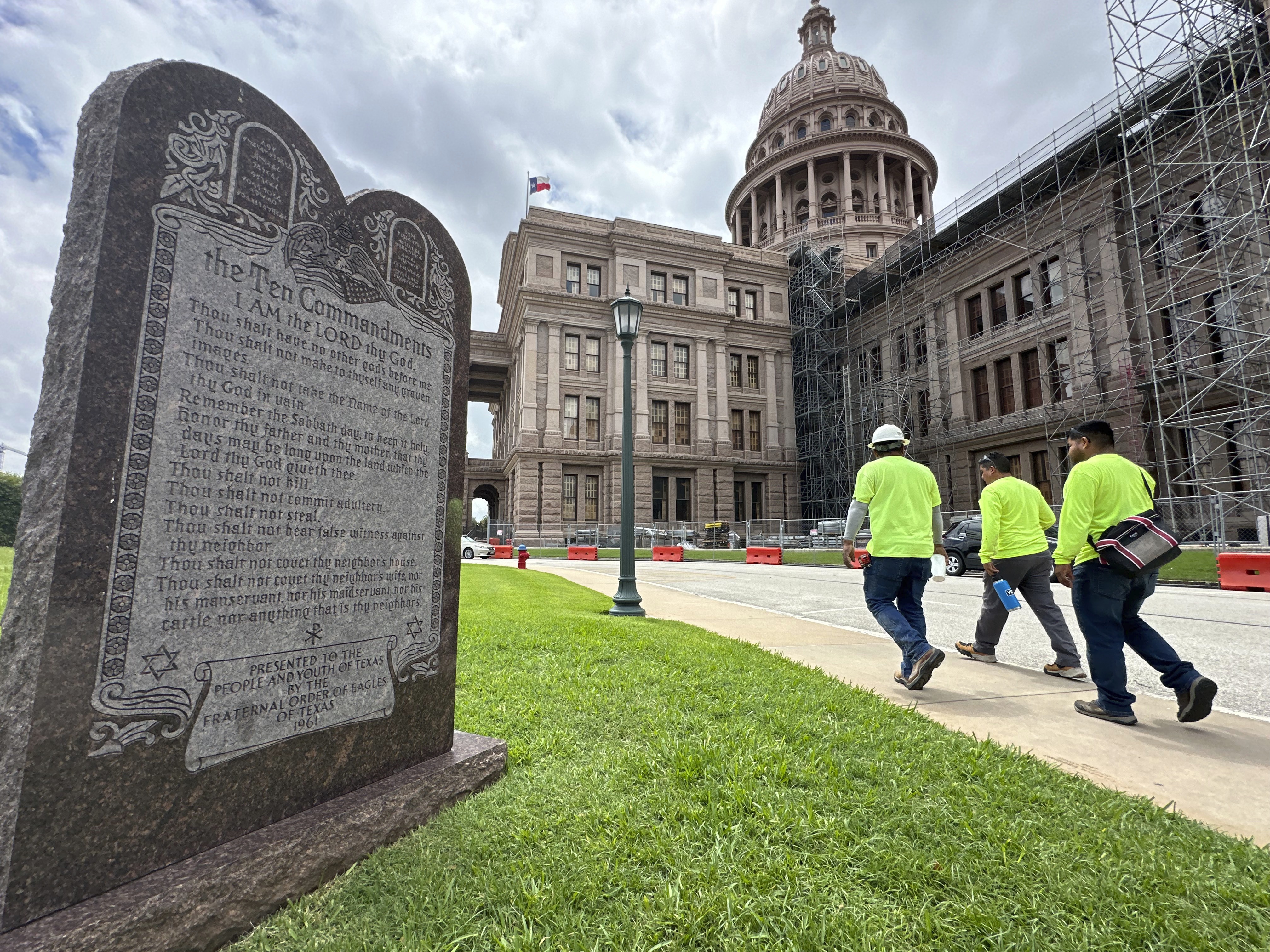 caption: Construction workers walk past a monument with the Ten Commandments outside the Texas Capitol in Austin last year.