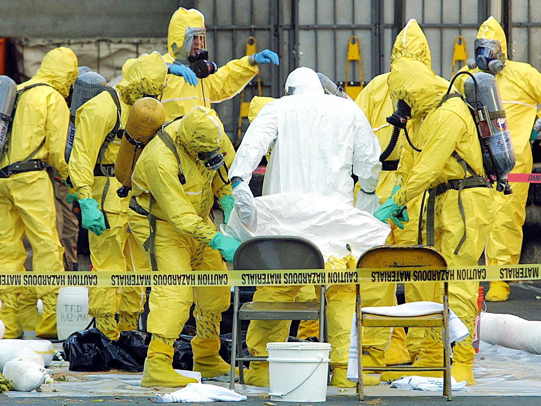 caption: Members of a haz-mat team help remove a hazardous materials suit from an investigator (in white) who emerged from the U.S. Post Office in West Trenton, N.J., on Oct. 25, 2001. Samples from the facility were part of an investigation into letters containing anthrax.