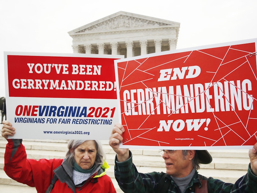 caption: Sara Fitzgerald and Michael Martin, both with the group One Virginia, protest gerrymandering in front of the Supreme Court in March 2018.